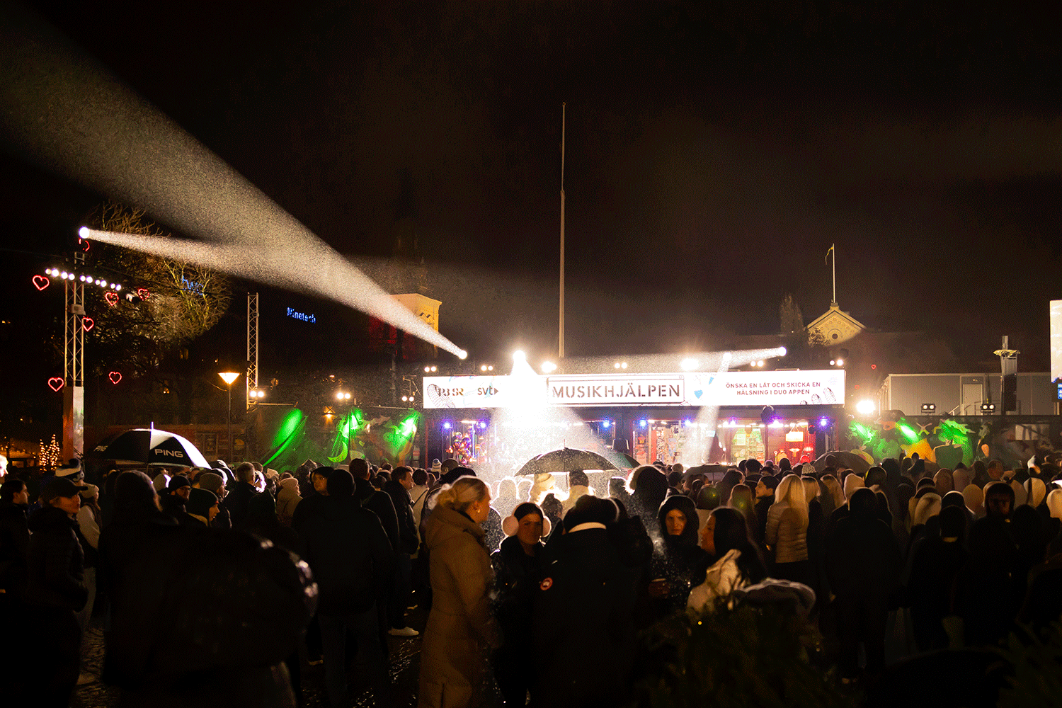 Torget i Karlstad när Musikhjälpen hade sin bur där. Strålkastarna på ett paraply i publiken så man ser att det regnar.