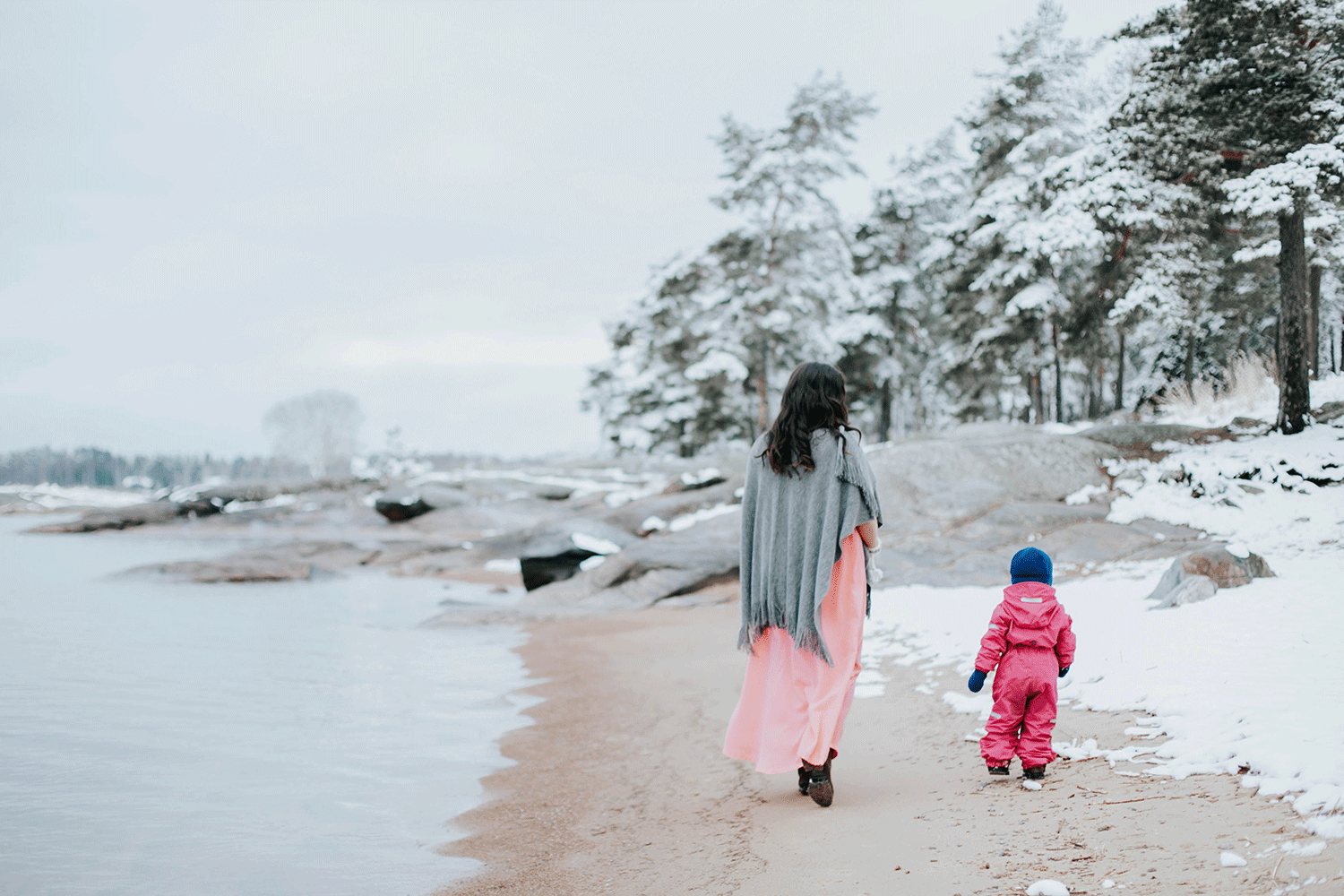 Mamma med barn går bort från kameran. Ett snöigt Skutberget. Båda har rosa på sig.