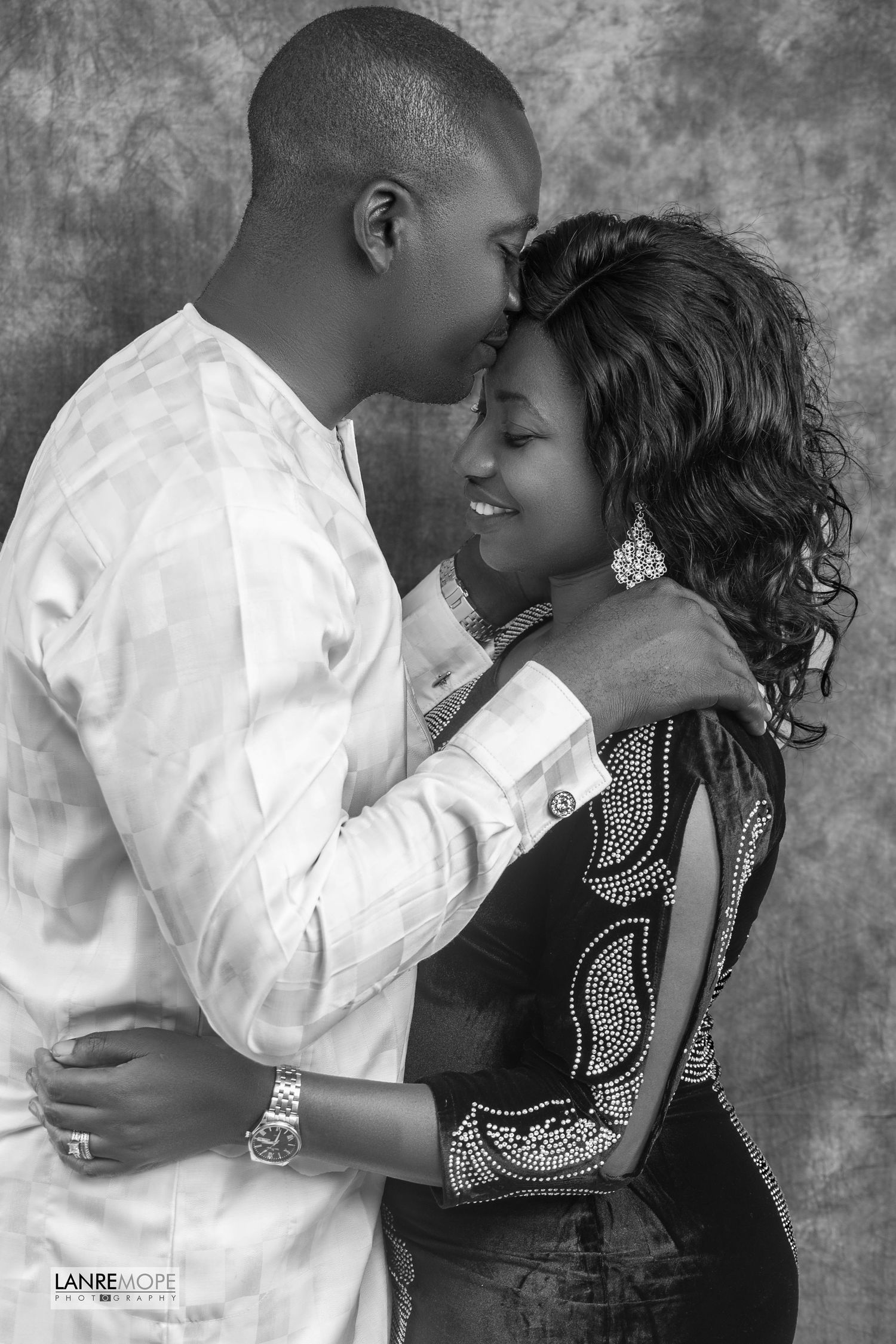 Romantic black and white portrait of an African couple embracing in a studio setting.