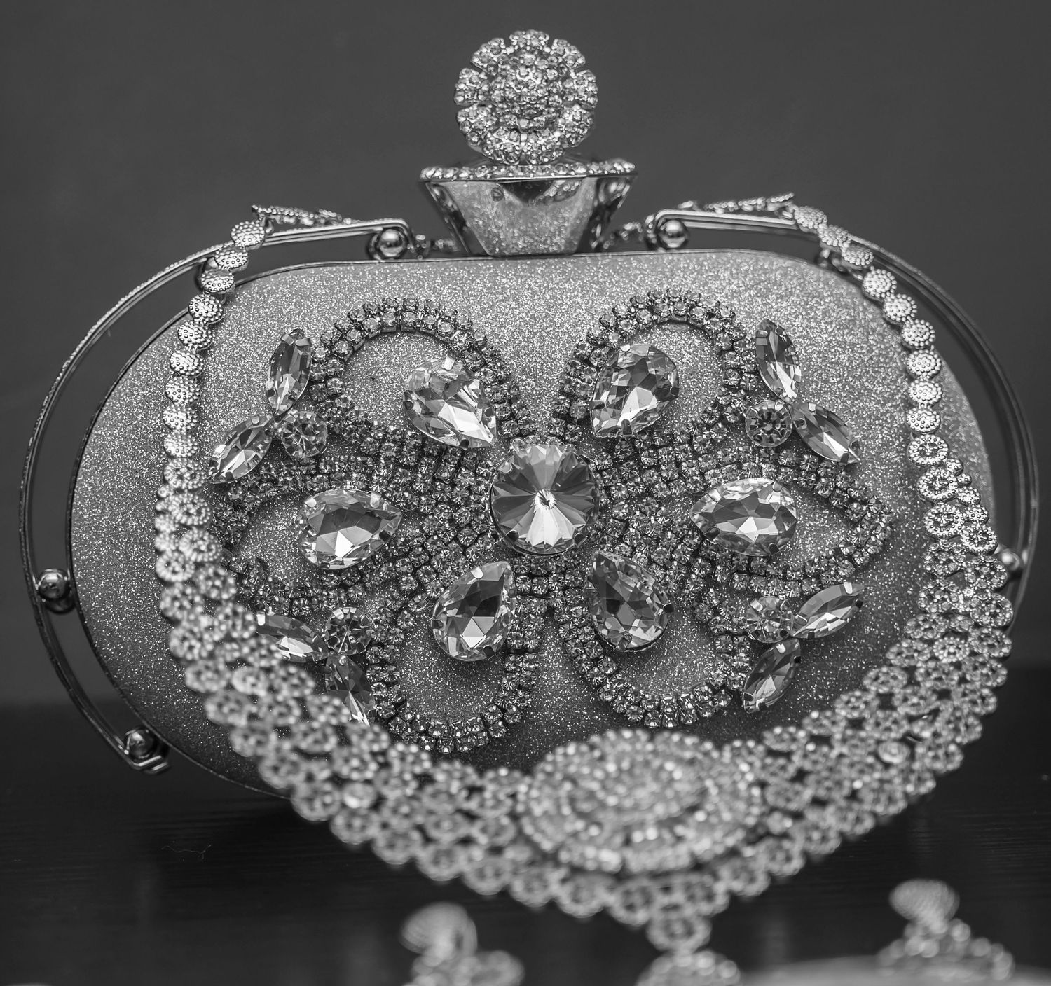 Ornate silver evening clutch bag adorned with crystals and gemstones in black and white photo.