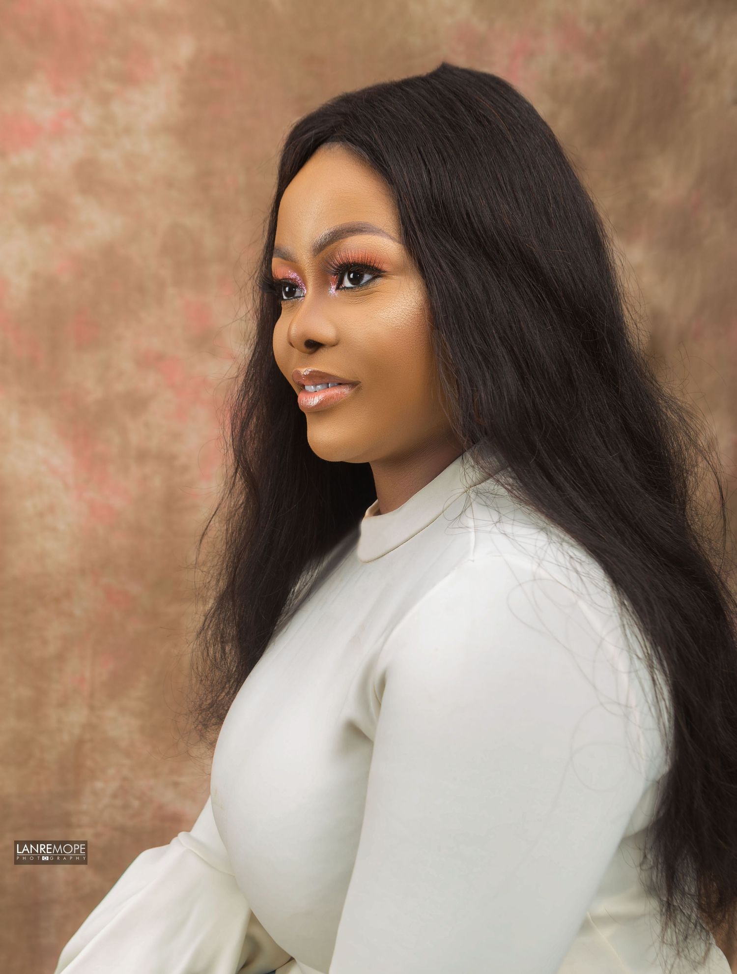 Woman with long straight black hair in white turtleneck top in professional studio portrait photo.