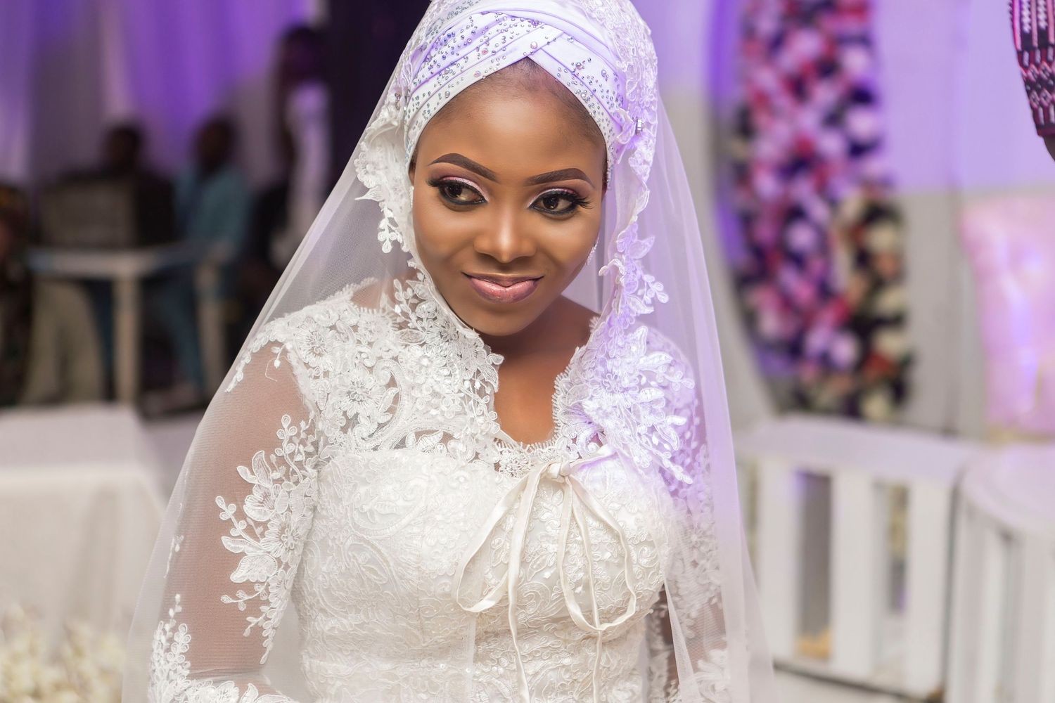 Beautiful bride in white lace wedding gown and veil smiling at elegant wedding ceremony.