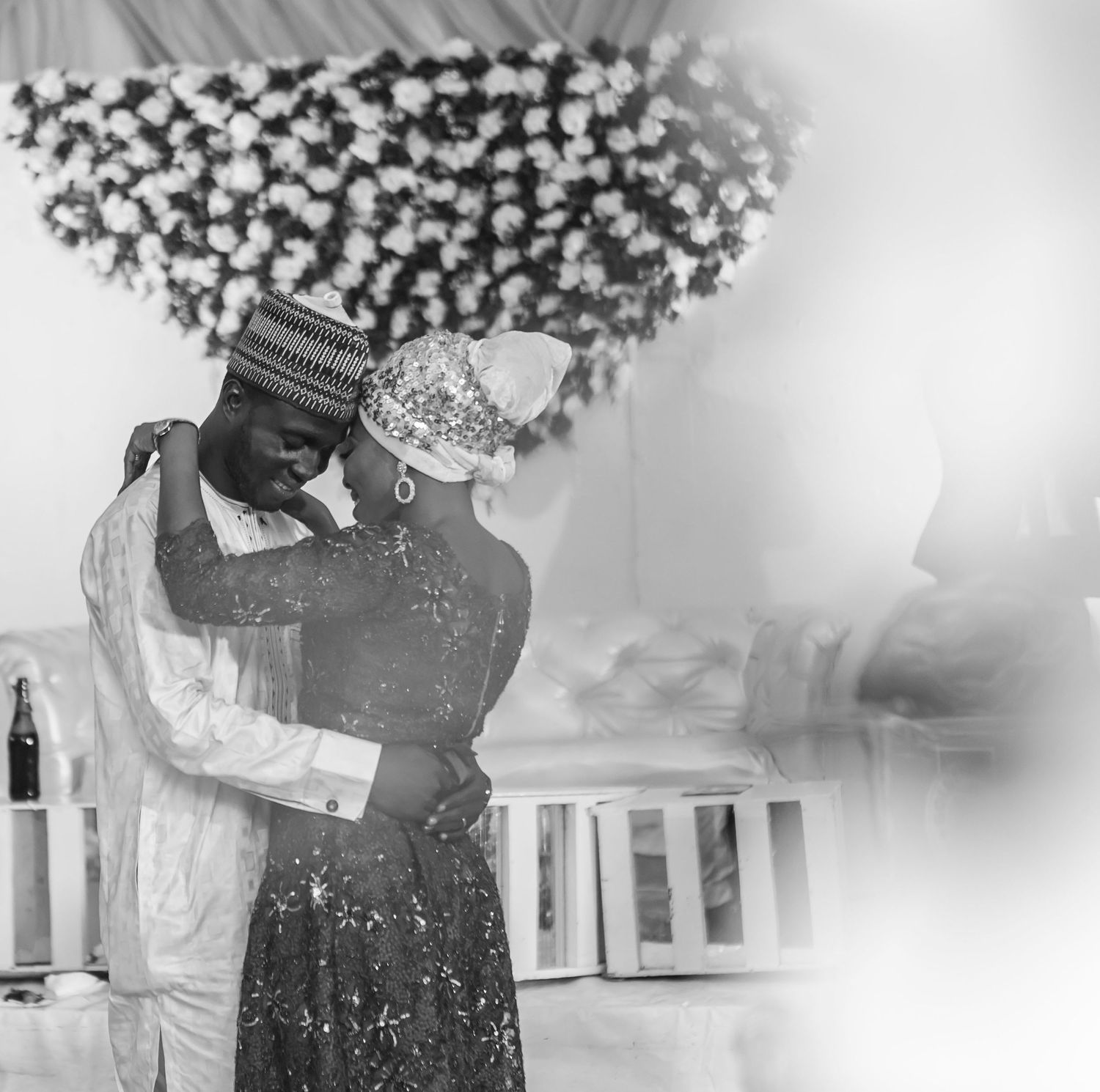 Black and white photo of a couple sharing a tender embrace at a traditional Nigerian wedding ceremony.