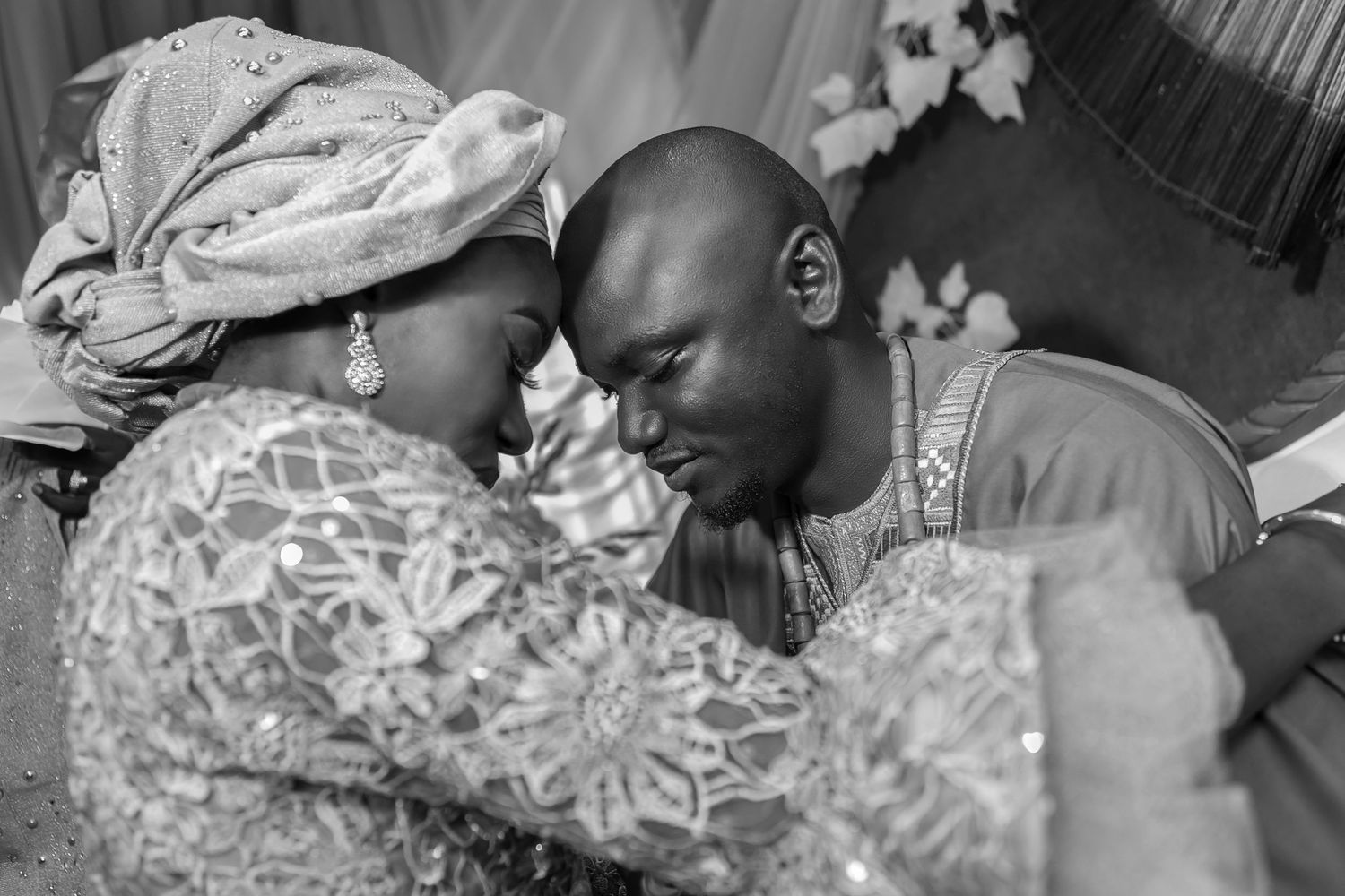 Intimate black and white portrait of a Nigerian bride and groom touching foreheads at their wedding.