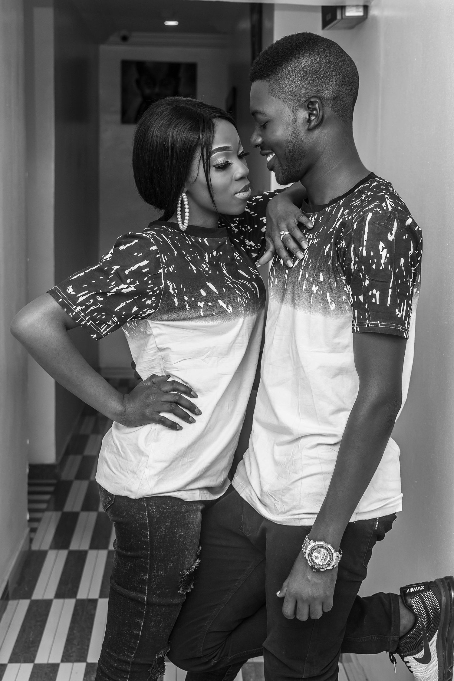 Black and white portrait of young African couple in matching shirts posing together.