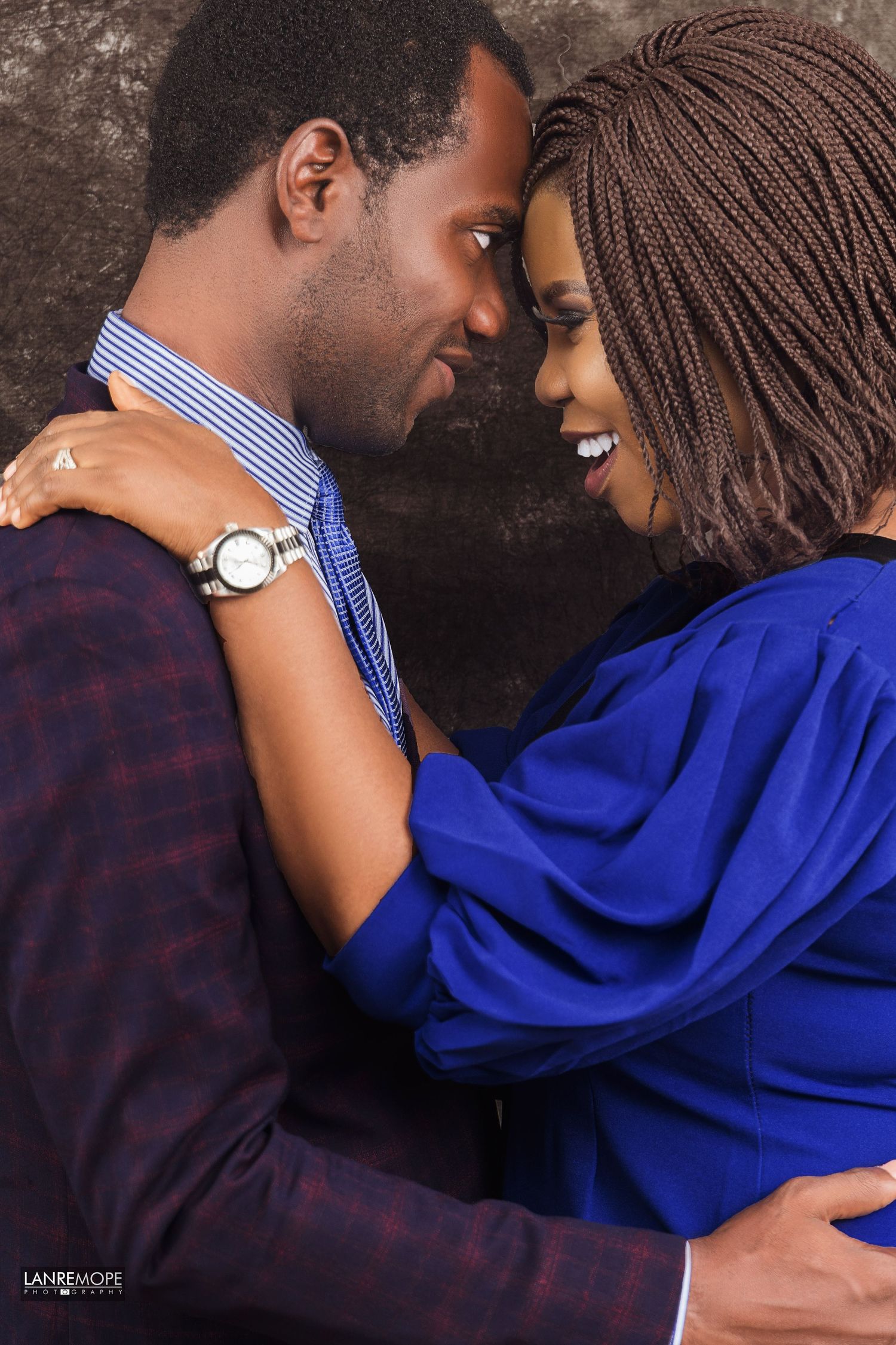 Romantic African couple in elegant attire sharing an intimate moment, woman in blue dress.