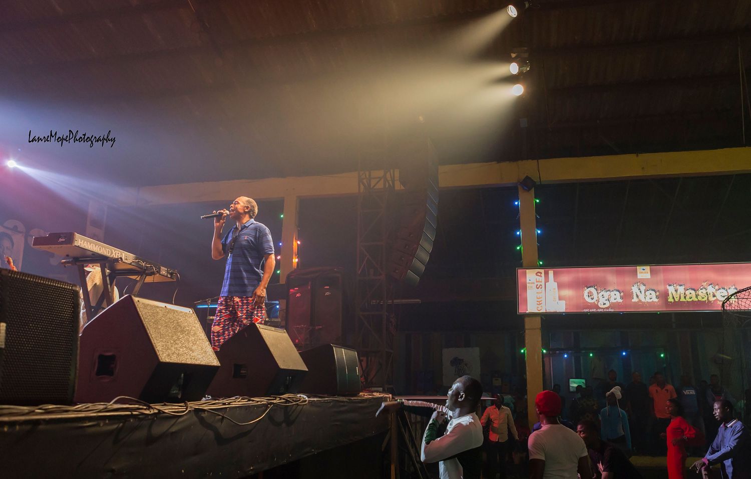 Live concert performer singing on stage with dramatic lighting and fog at an outdoor music venue.