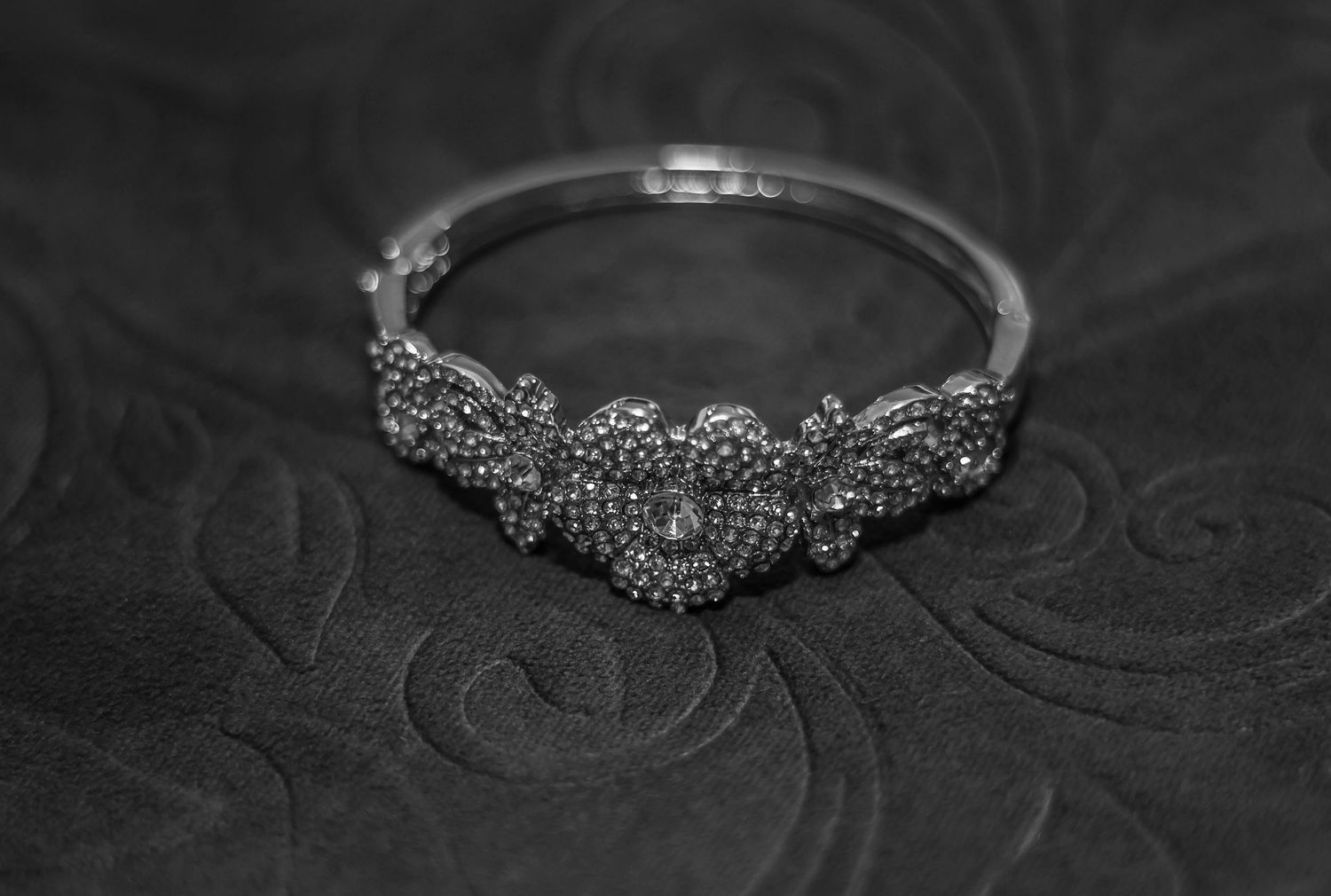 Elegant silver floral bracelet bangle with intricate marcasite detailing on dark textured background.