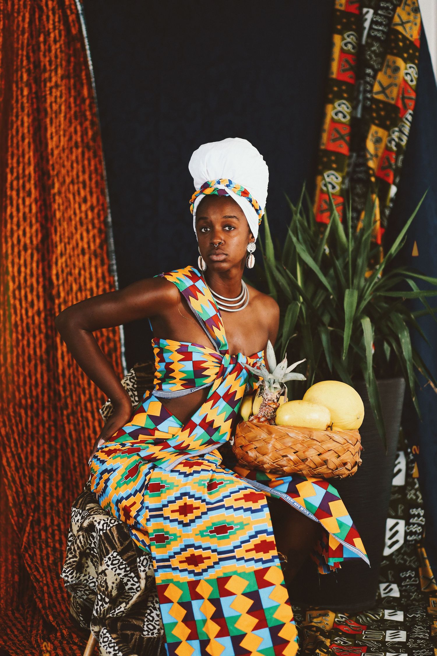 Modelo negra em ensaio artístico com vestimenta inspirada na cultura africana e frutas.