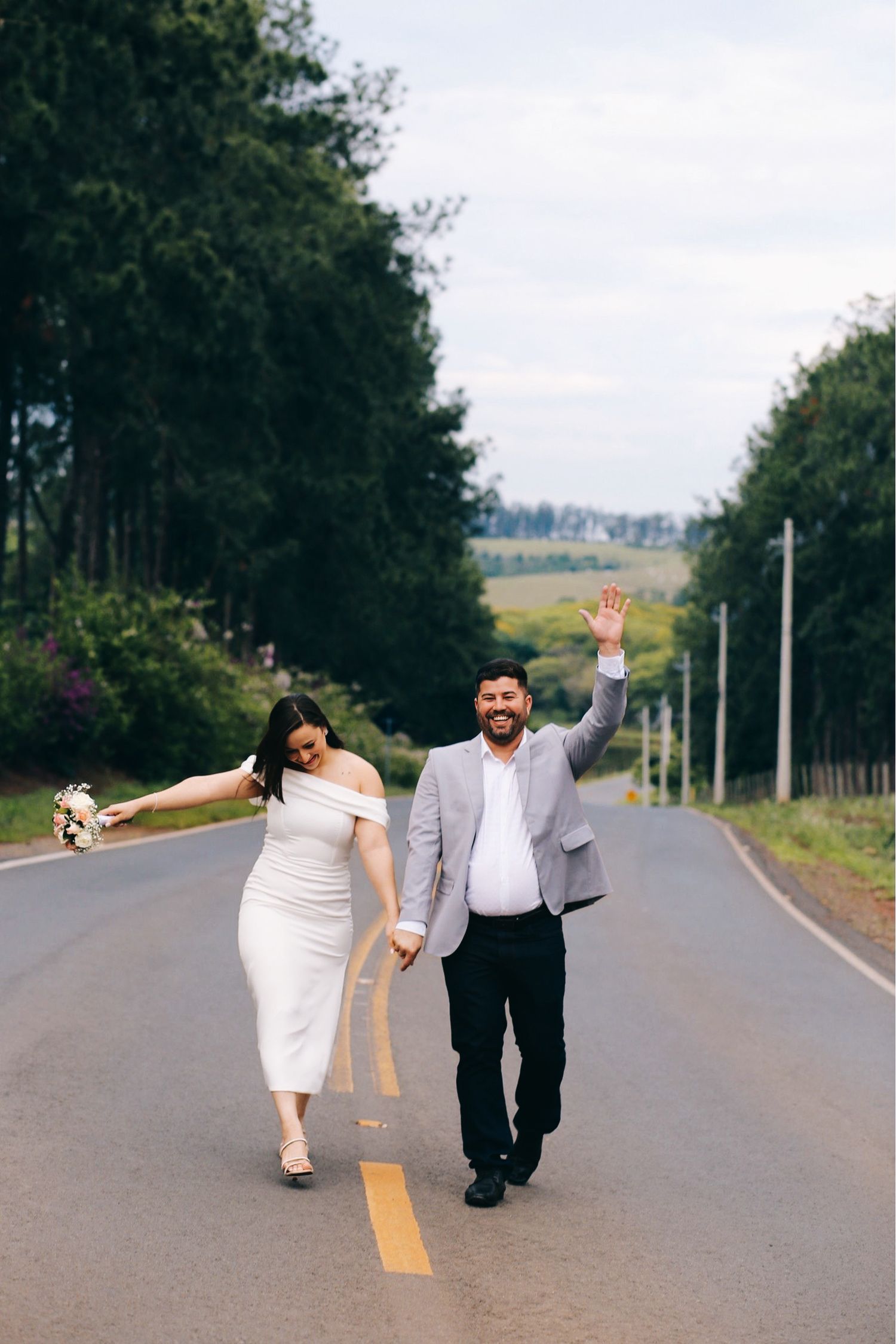 Casal de recém-casados comemorando em uma estrada após o casamento civil.
