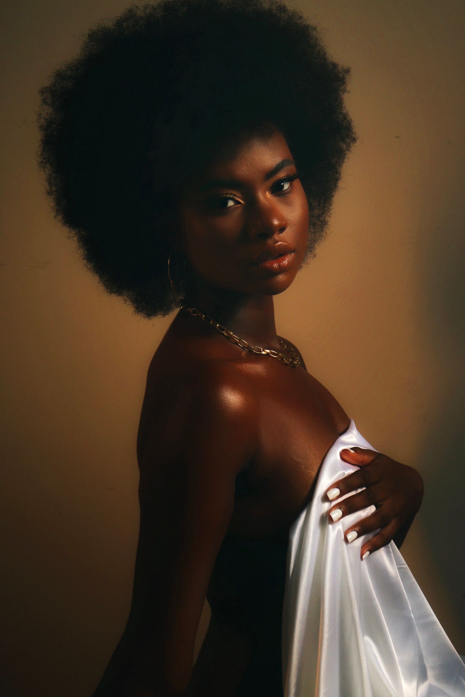 Retrato artístico de modelo negra em ensaio seminu com iluminação natural.
