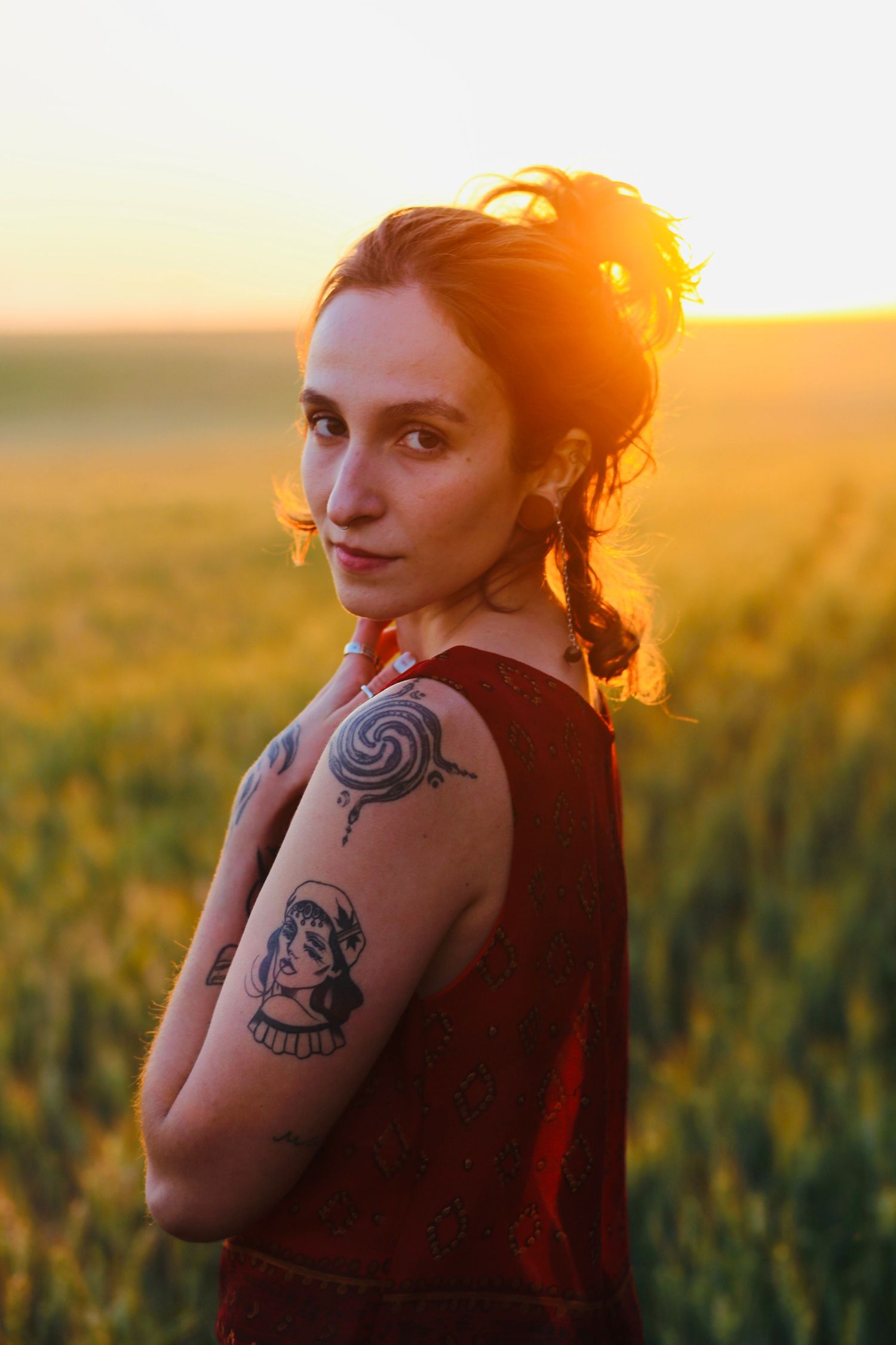 Mulher em ensaio fotográfico em uma plantação ao pôr do sol.