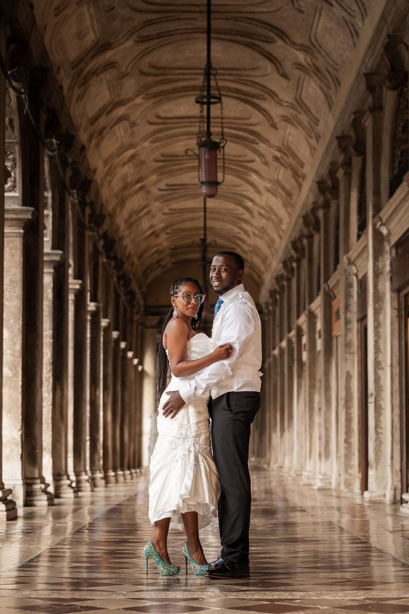 Couple embracing in a grand marble colonnade during Venice wedding photoshoot.