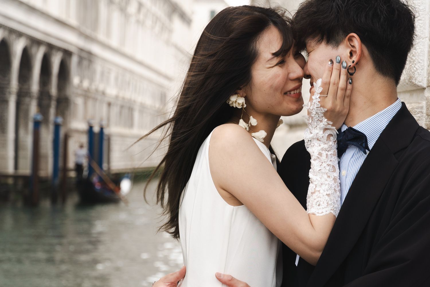 Romantic couple sharing an intimate moment in Venice, Italy, with gondolas and historic architecture in the background.