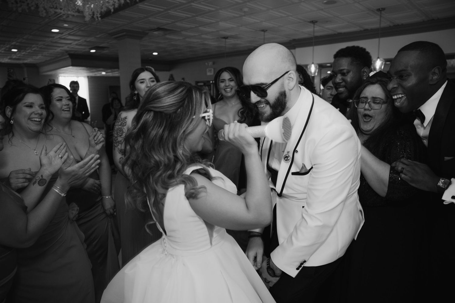 Bride and groom share a joyful dance together at their wedding reception surrounded by celebrating guests.