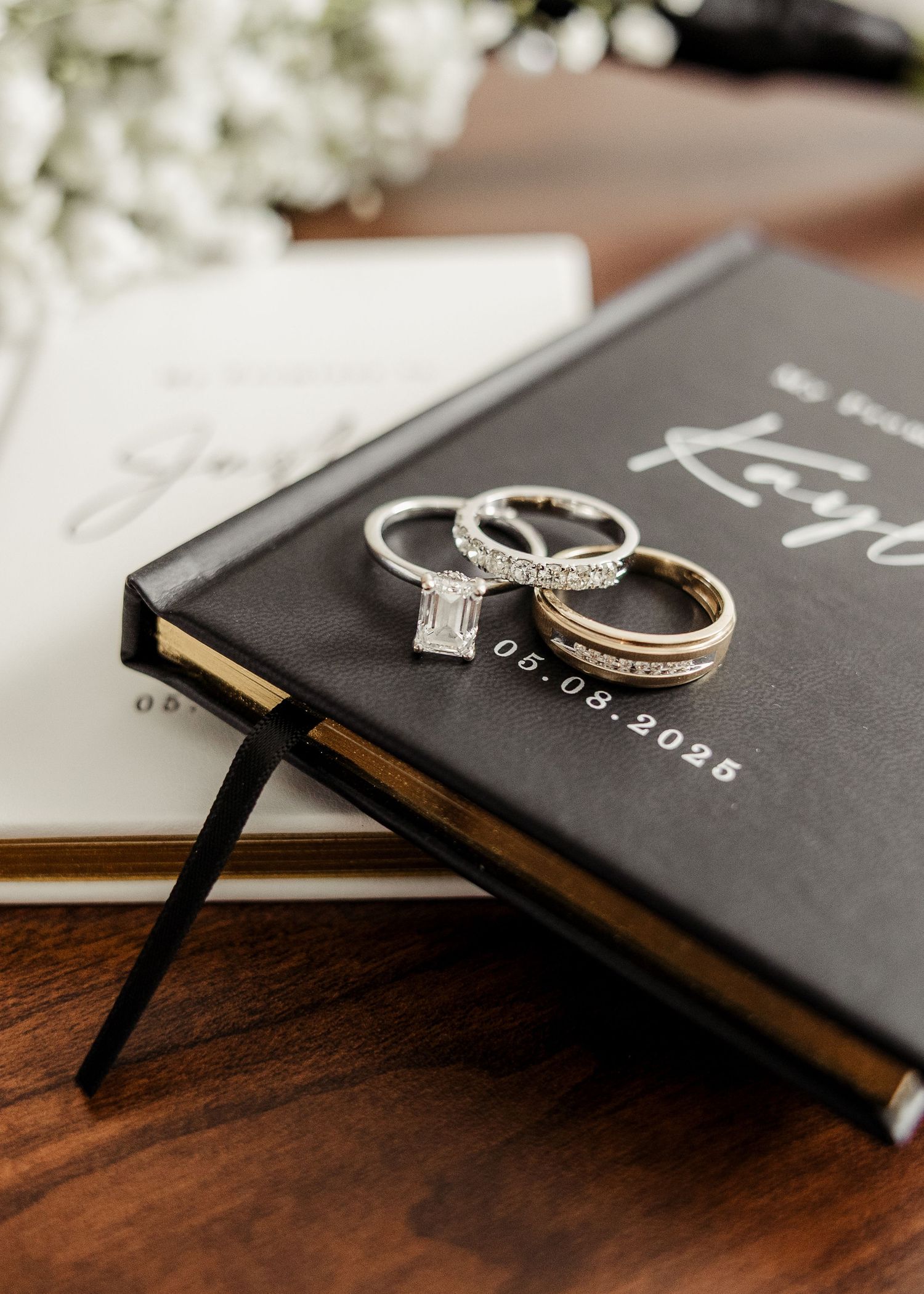 Elegant wedding rings displayed on a personalized black wedding vow book dated 06.08.2025.