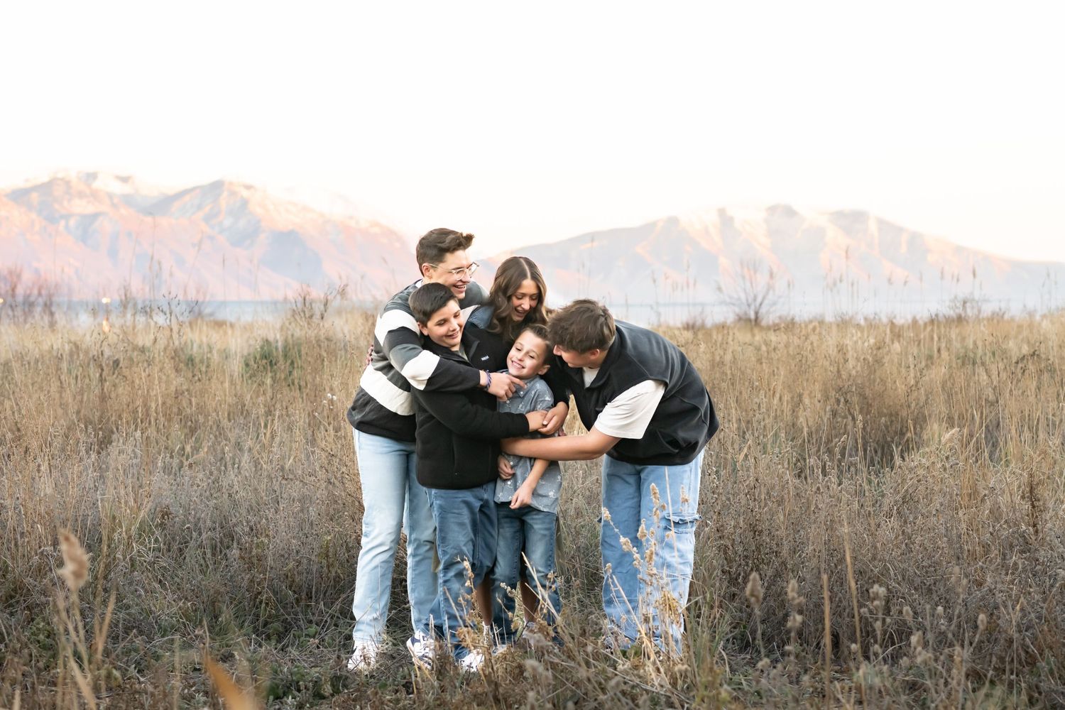 Family sharing a heartfelt group hug during an outdoor mountain family photography session.