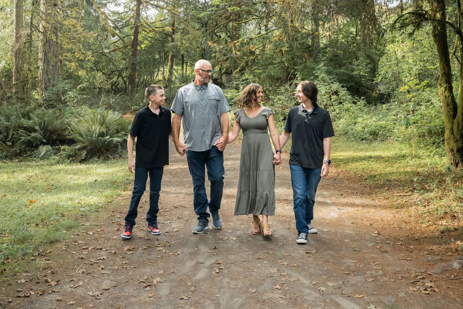 Family walking together through a wooded trail during a relaxed outdoor family photography session.