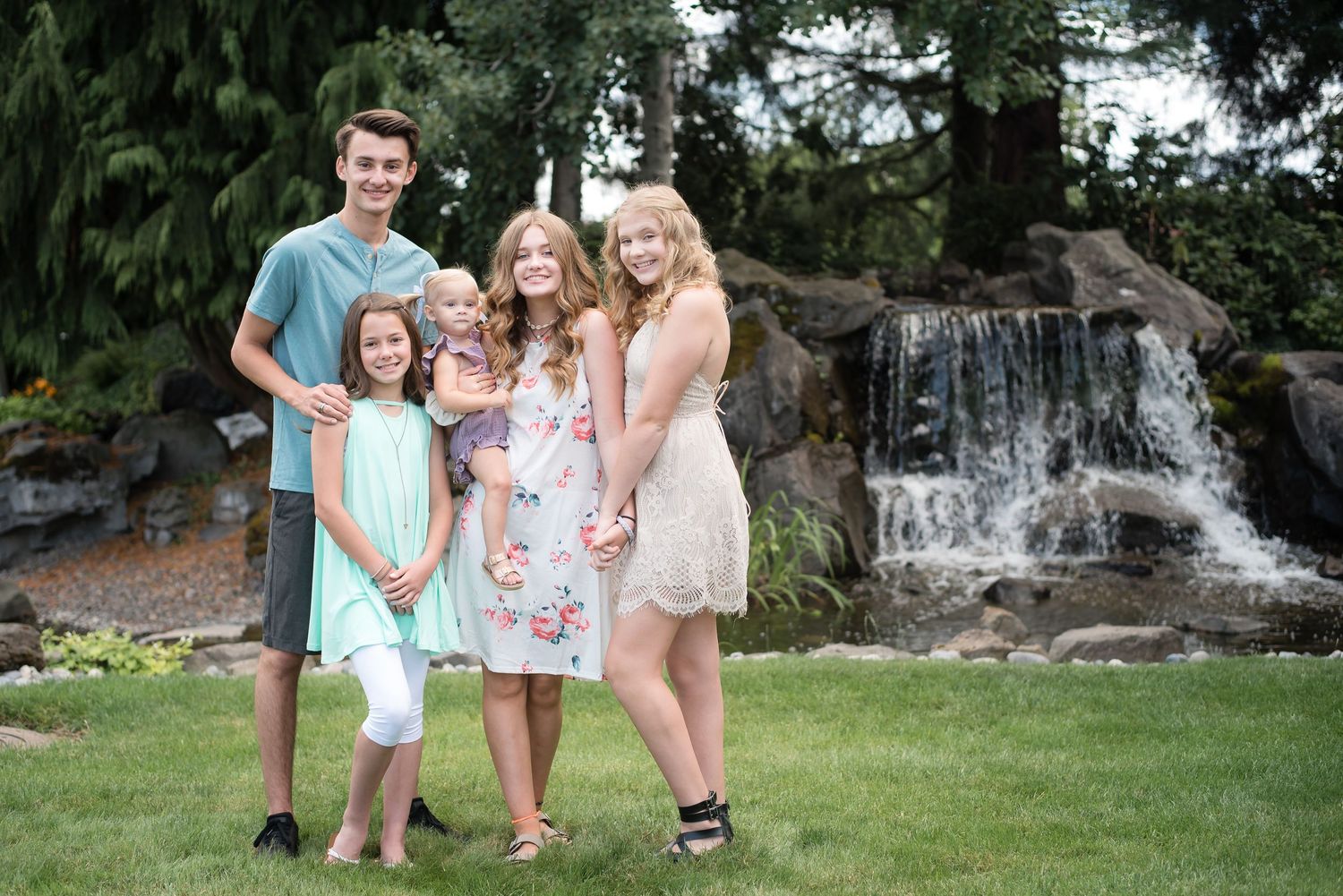 Five cousins smiling together during an outdoor family photography session by a waterfall in Washington.