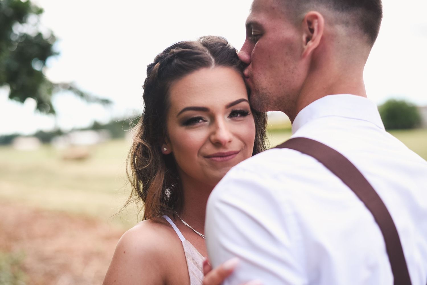 Close-up portrait of the bride and groom embracing on their wedding day with natural light.