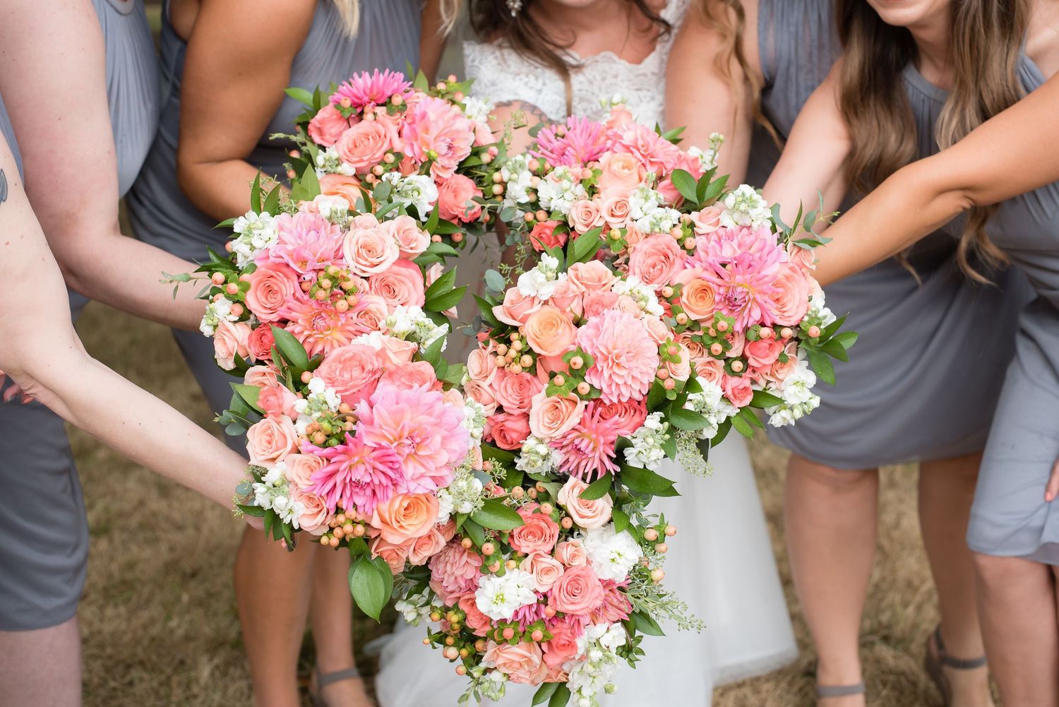 Close-up wedding detail of a colorful bridal bouquet with bridesmaids gathered around.
