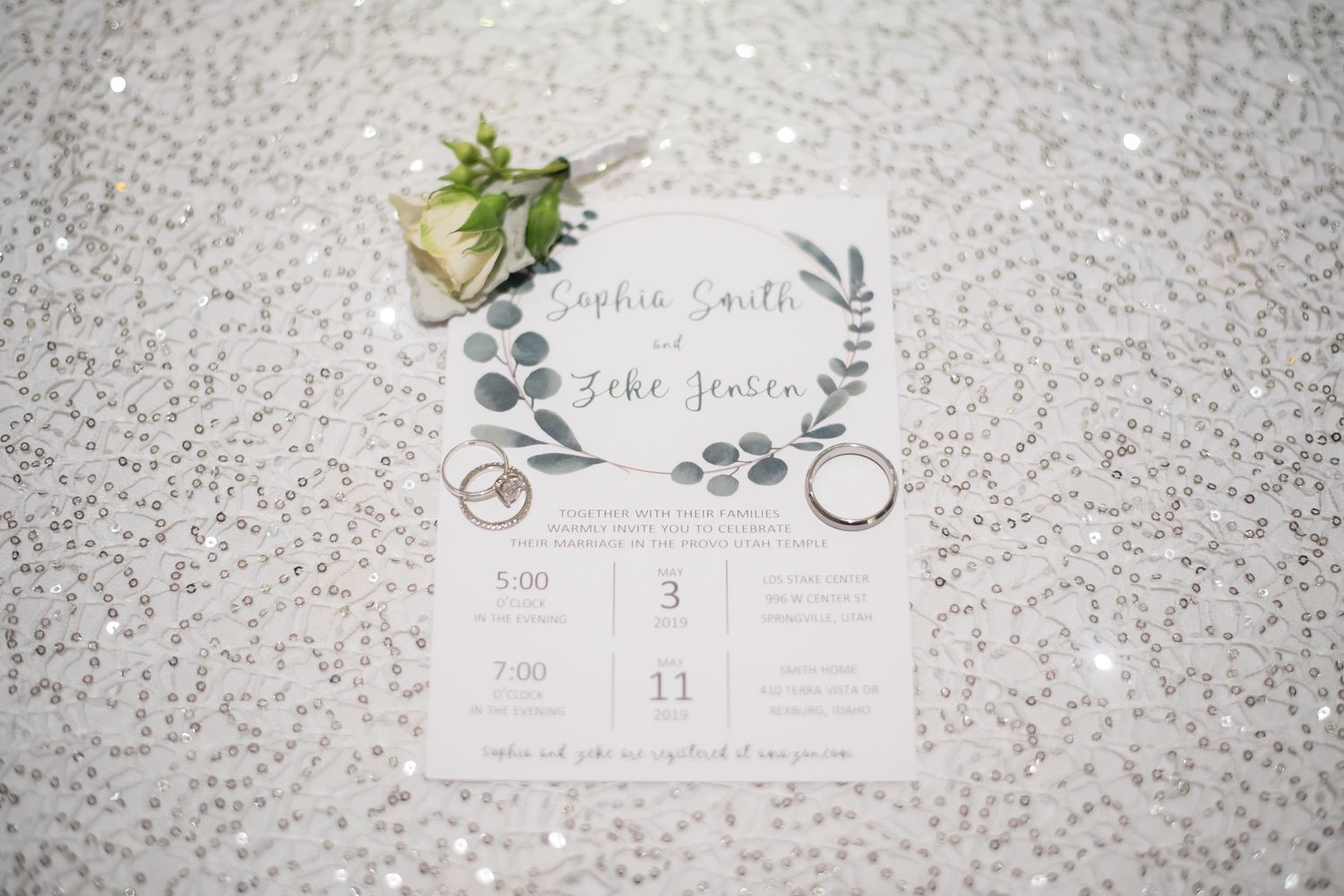 Elegant wedding invitation suite with rings and greenery styled for wedding detail photography.