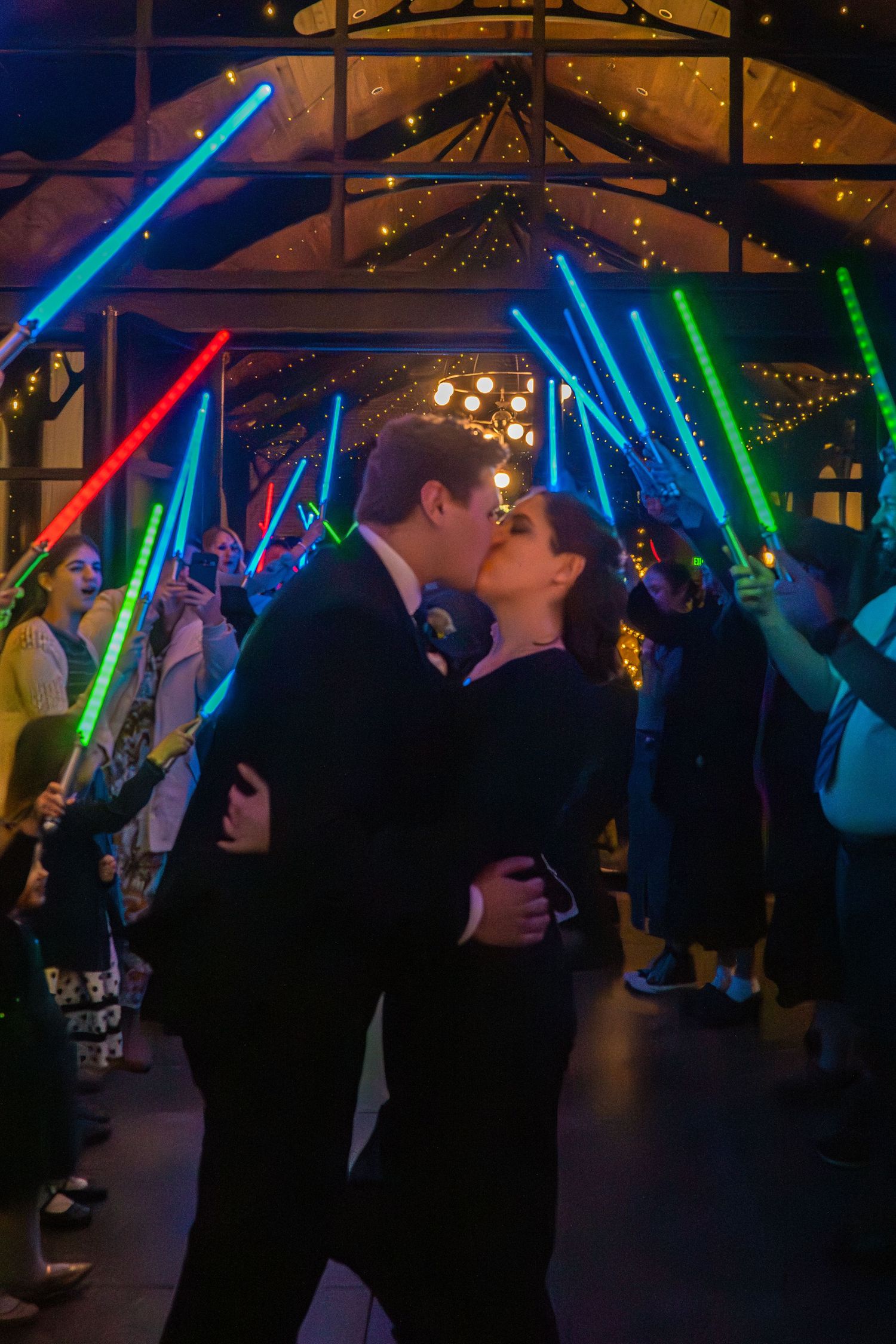 Bride and groom sharing a romantic dance beneath colorful reception lights during their wedding celebration.