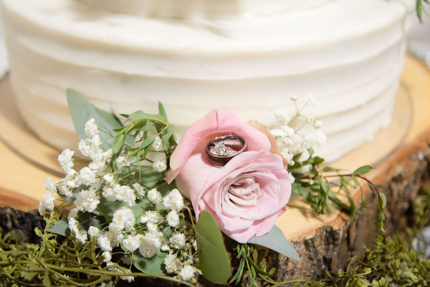 Close-up of a wedding cake decorated with fresh flowers during a wedding reception.
