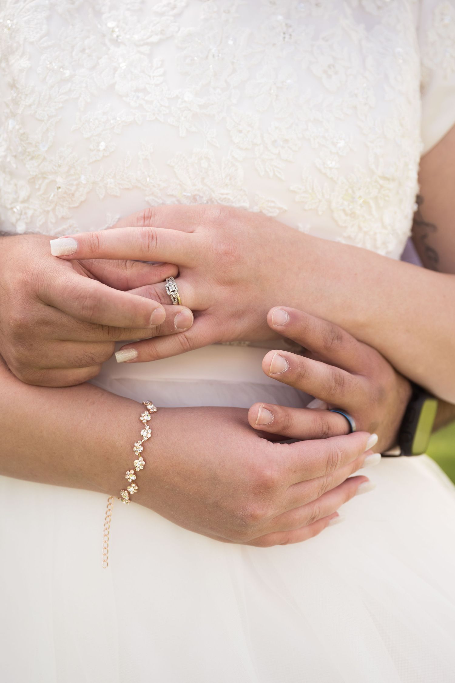 Close-up of the couples hands highlighting their wedding rings and elegant bridal details.