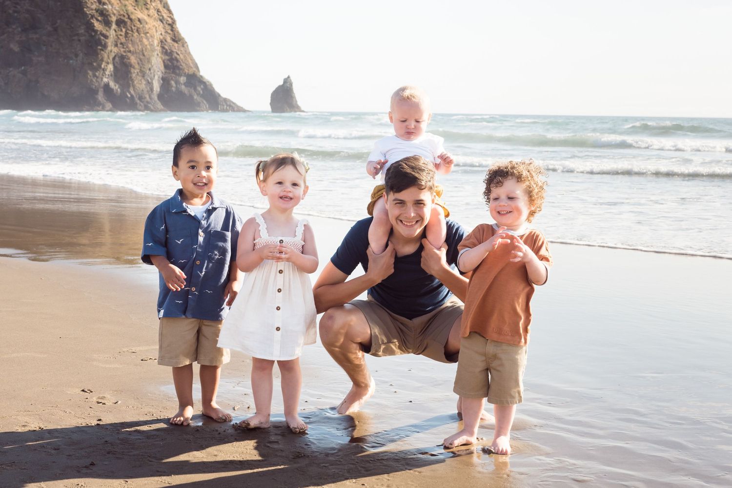 Family playing at Cannon Beach in Oregon during a relaxed outdoor family portrait session at sunset.