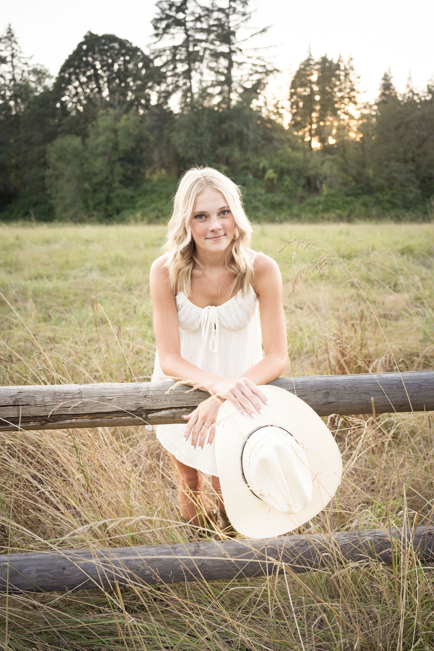 Natural light senior portrait featuring a young woman in a peaceful country field with cowboy hat.