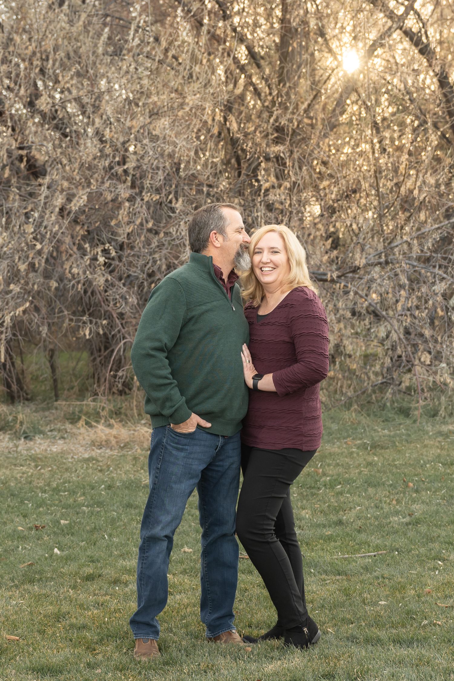 Couple embracing during a romantic outdoor portrait session at golden hour.