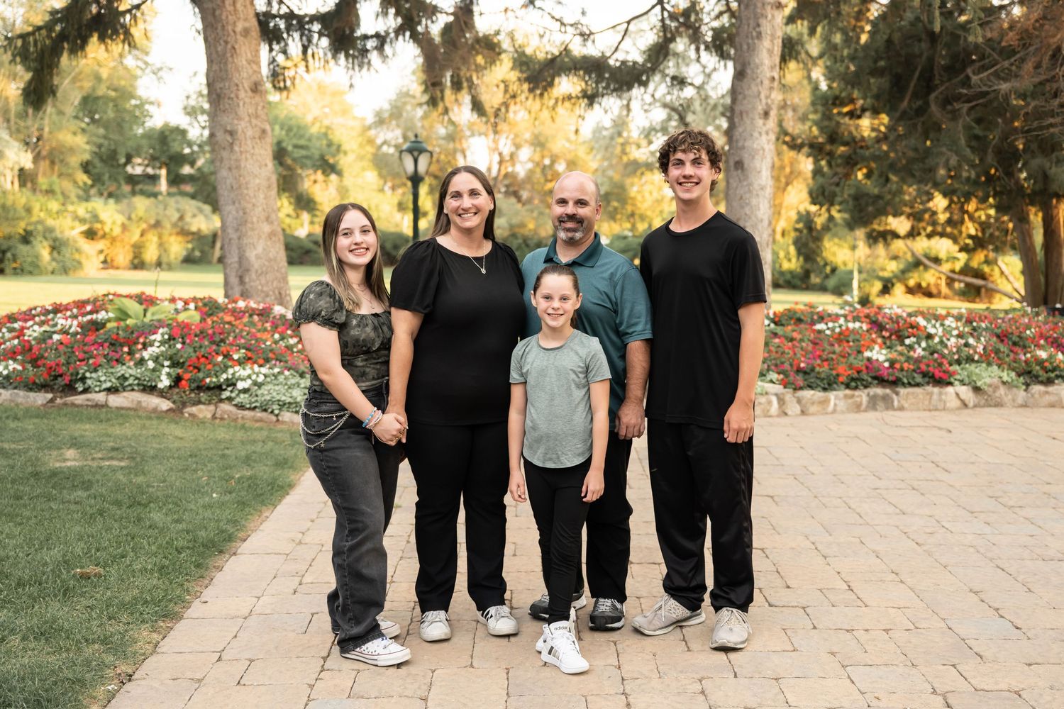 Family of four smiling together in a beautiful garden during an outdoor family photography session.