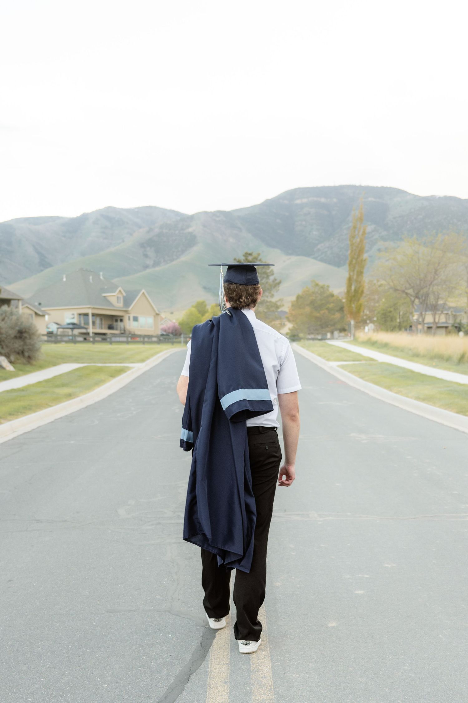 High school graduate walking down a scenic road during a graduation photography session in Utah.