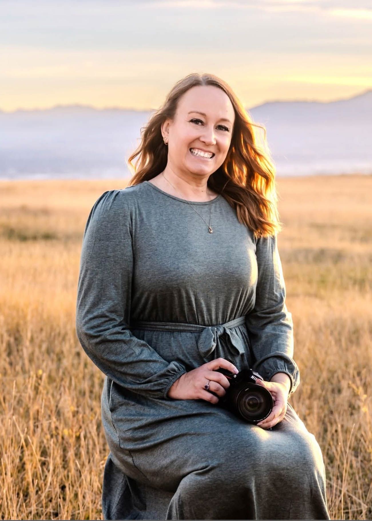 Jen Verbeck Photography posing in an open field with a camera for a headshot.