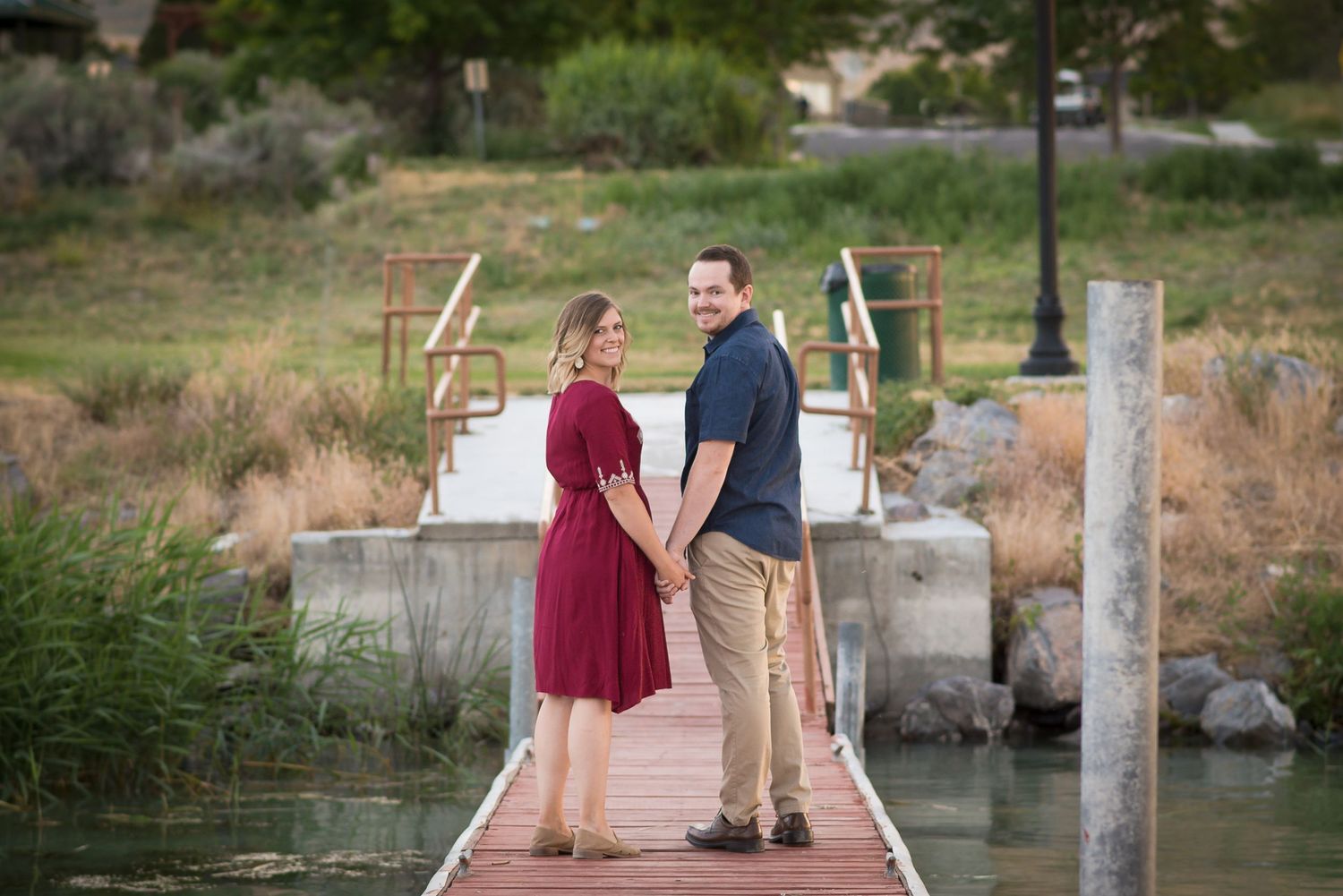 Romantic couple portrait captured on a dock over a lake in a peaceful outdoor setting.