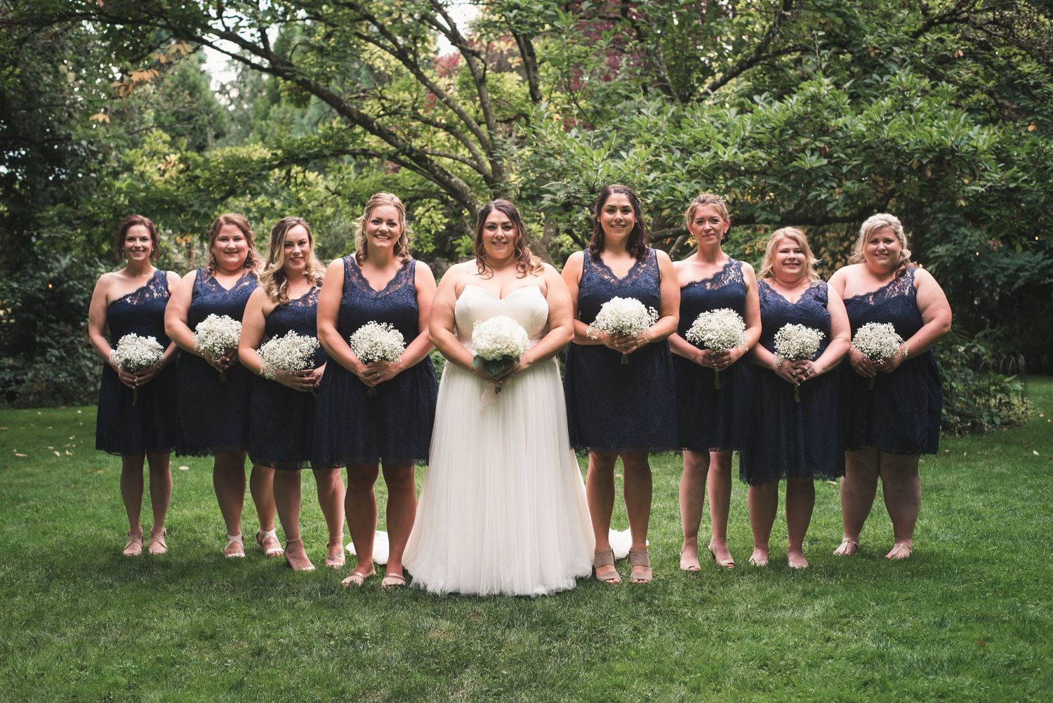 Wedding party portrait featuring the bride and bridesmaids in coordinated dresses.