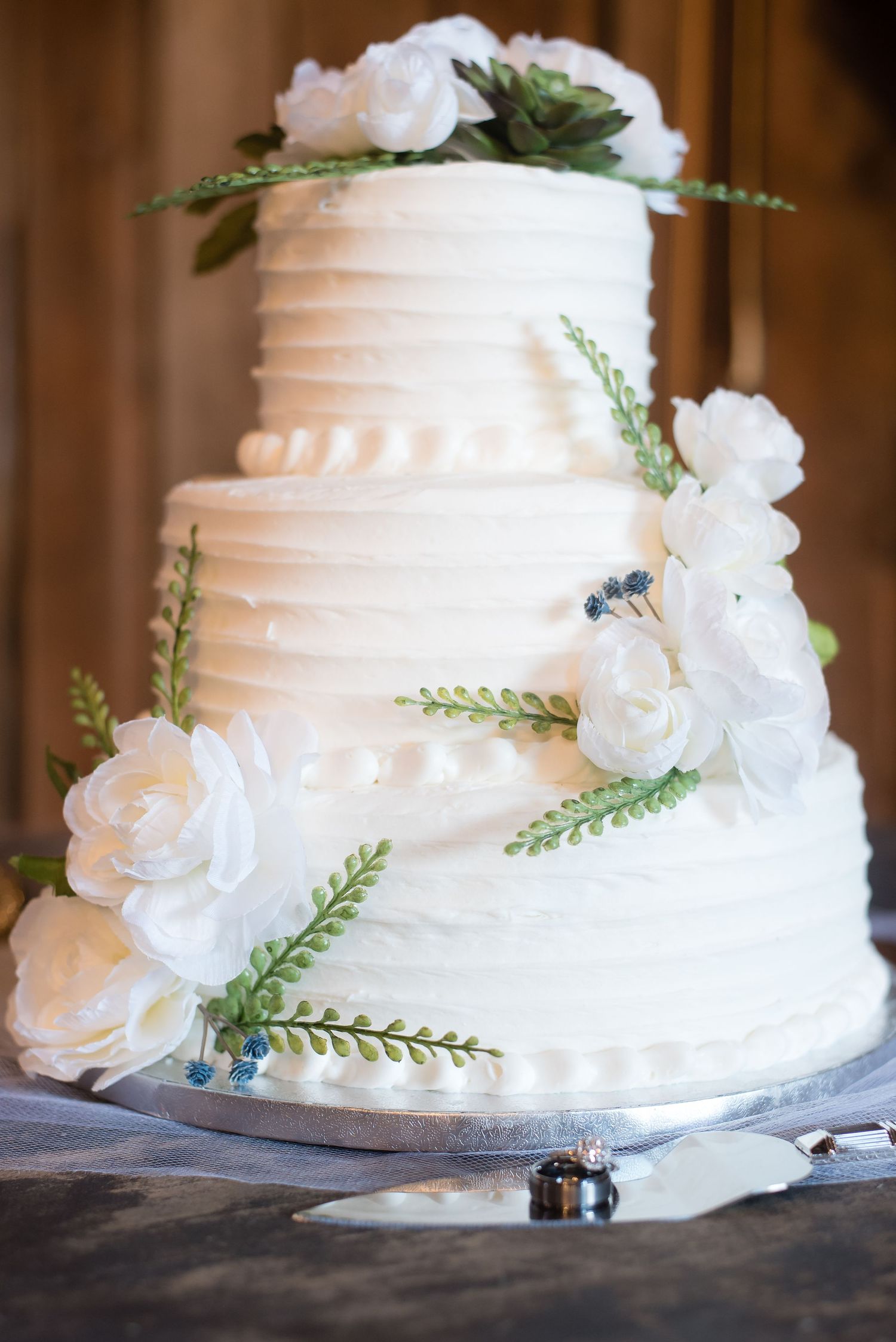 Elegant tiered wedding cake decorated with artificial flowers for a beautiful wedding reception.