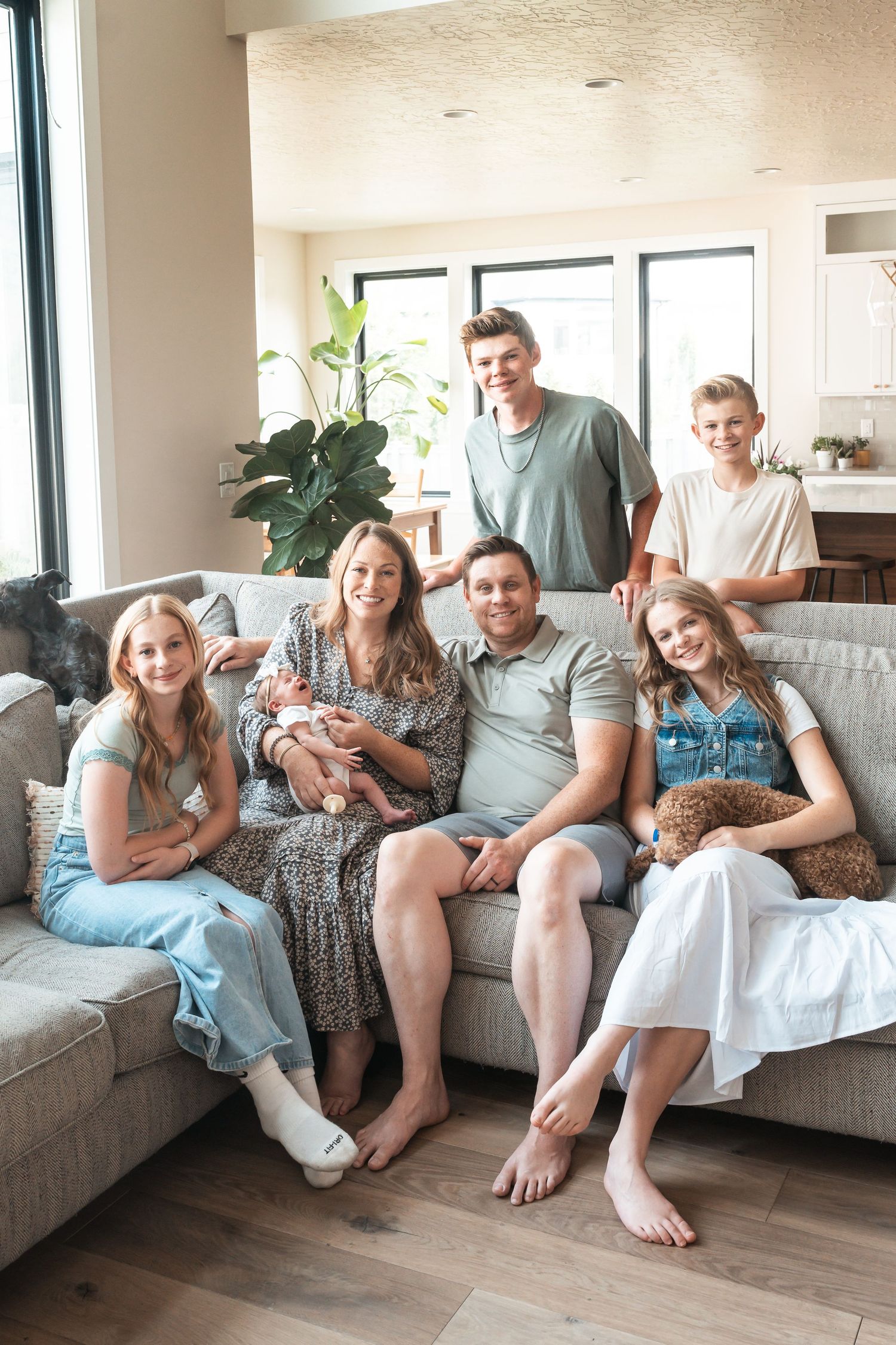 Multi-generational family gathered together in a bright living room during an in-home lifestyle family photography session.