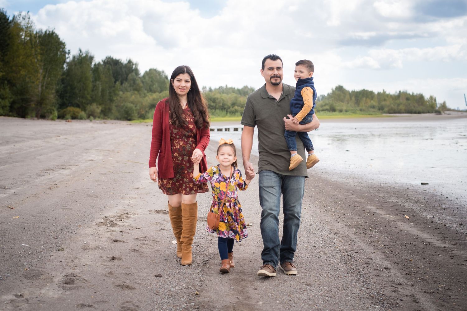 Natural light family portrait capturing parents and children enjoying a scenic riverside walk.