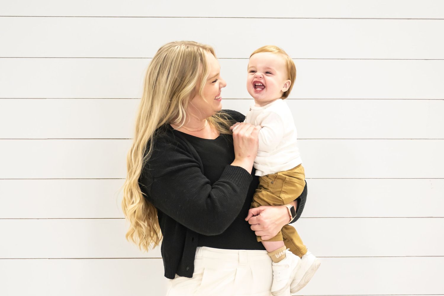 Mother holding her smiling toddler during an indoor studio family photography session in Utah County.