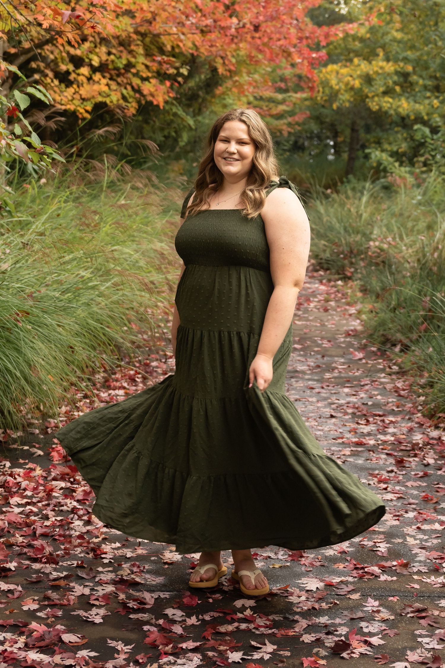 High school senior girl in a flowing black dress surrounded by vibrant autumn leaves during a fall senior portrait session in Utah.