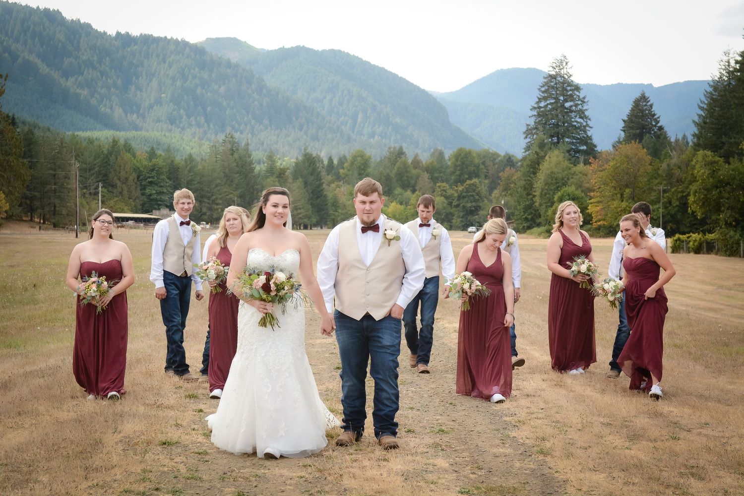 Bride, groom, and wedding party walking with scenic mountain views during an outdoor wedding celebration.