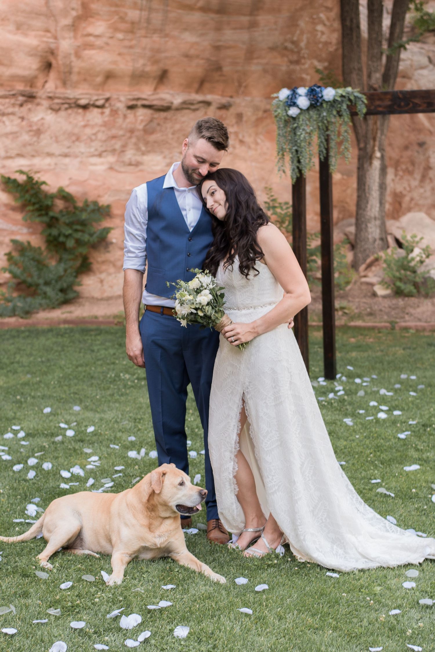 Bride and groom sharing a joyful wedding portrait with their dog after the ceremony.