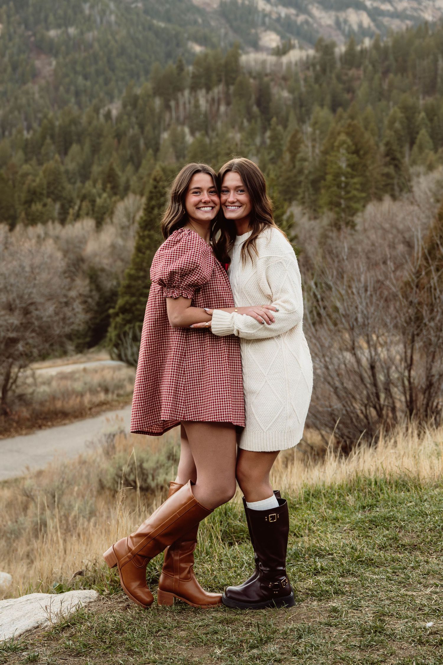 Sisters embracing in a scenic mountain field during a natural outdoor portrait session.