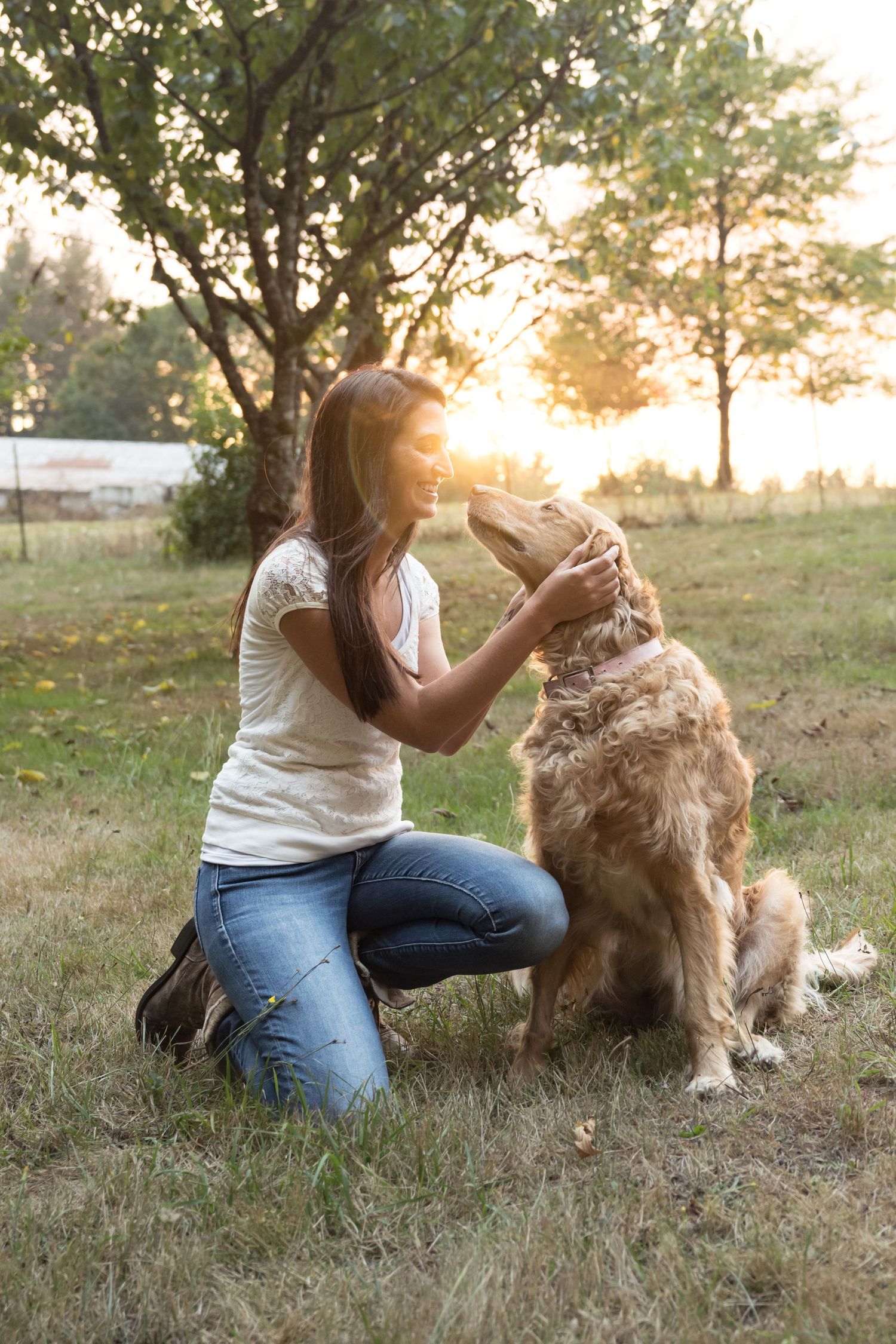 Woman sharing a sweet moment with her Golden Retriever during a golden hour portrait session.