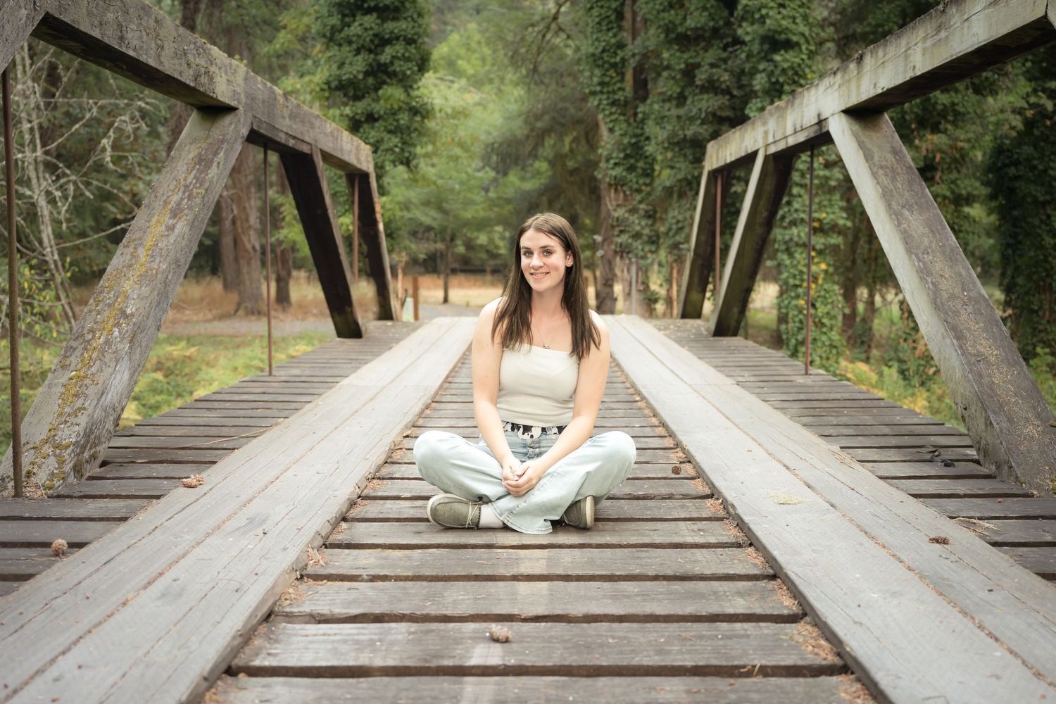 High school senior girl sitting on a wooden bridge during an outdoor senior photography session in Washington.