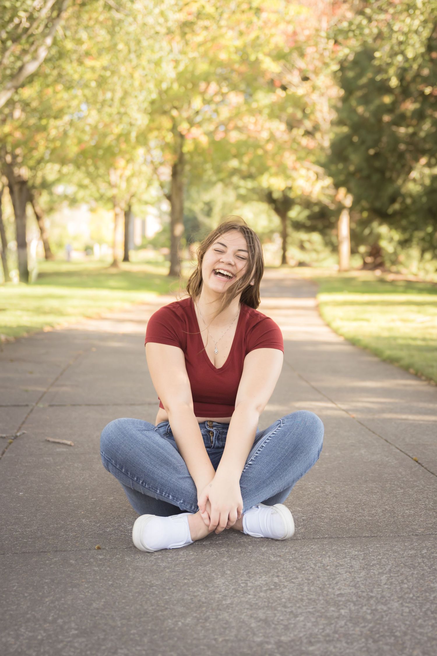 High school senior girl sitting on a quiet road during an outdoor senior photography session in Washington.