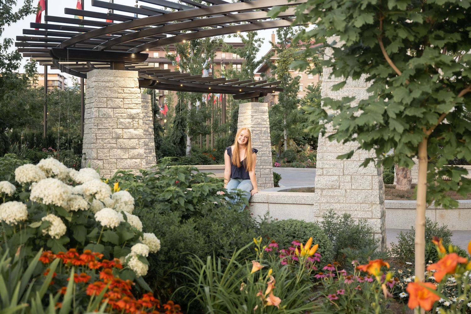 High school senior portrait captured in a beautiful garden with stone columns, flowers, and natural light during a Utah photography session.