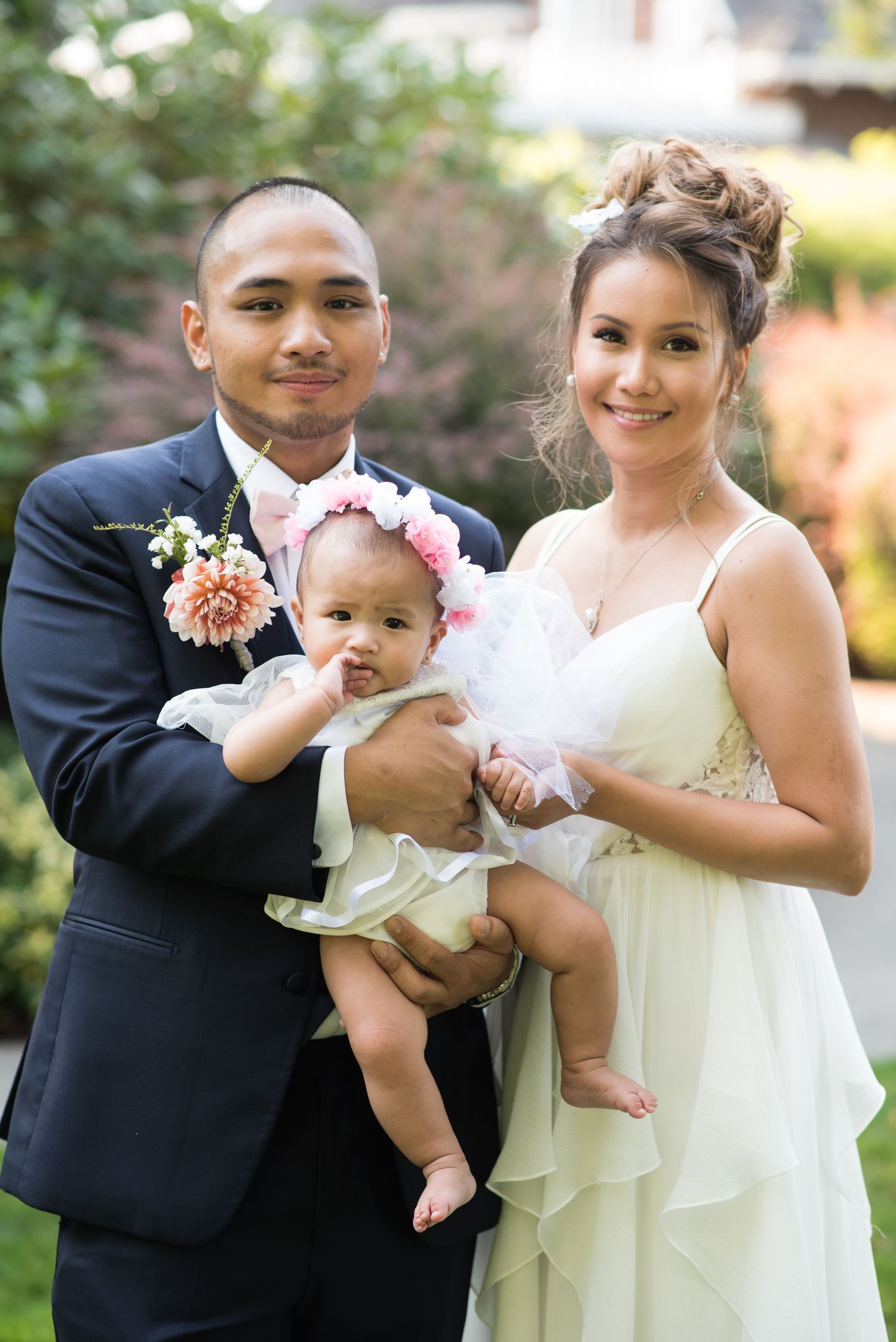 Natural light wedding portrait featuring newlyweds celebrating with their child.